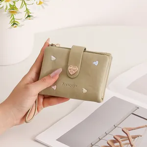 Close-up of olive green wallet featuring heart-shaped clasp and delicate embroidery