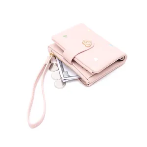 Detailed macro view of pink heart embroidered wallet showing zipper pocket and wristlet strap