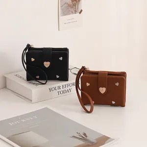 Detail of black and brown leather wallets with heart embroidery and wristlet straps.