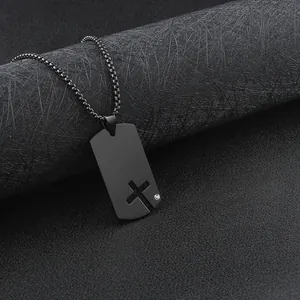 Close-up of black stainless steel dog tag necklace with cutout cross and rhinestone