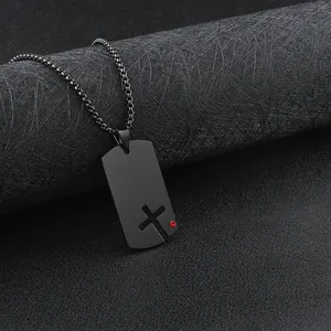 Detail view of a black stainless steel dog tag necklace with a hollow cross and red stone