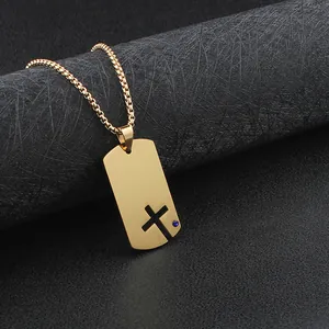 Detailed view of the hollow cross cutout and blue stone on a gold dog tag necklace