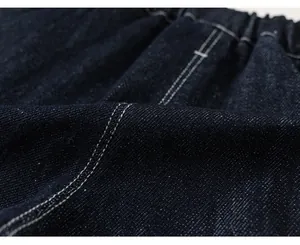 Dettaglio ravvicinato della trama del tessuto denim indaco scuro con cuciture bianche