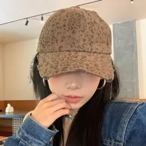 Woman wearing a vintage leopard print baseball cap with a denim jacket in a cafe setting