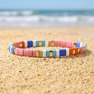 Detailed macro view of colorful enamel tila bead elastic bracelet on a sunny sandy beach