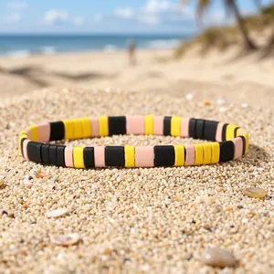 Detail of colorful enamel beaded stretch bracelet on a sunny beach sand background