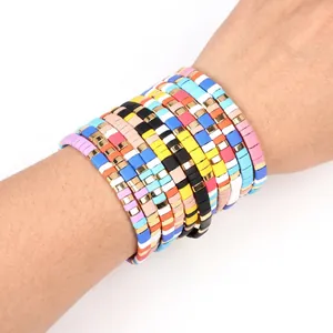 Close-up of colorful enamel beaded stretch bracelets stacked on a wrist.