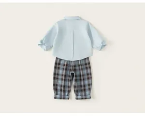 Back view of elegant boys light blue dress shirt and coordinating blue plaid trousers set