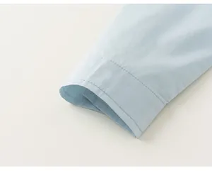 Detailed close-up of light blue cotton shirt cuff showing fine stitching and fabric