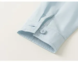 Close-up detail of a light blue boy's shirt cuff showing matching button and stitching