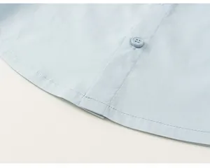 Detailed close-up showing the curved hem and matching button of this light blue boy's shirt