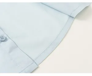 High-quality close-up of neat stitching and button on a light blue boy's formal shirt