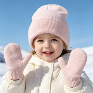 Detailed view of pink knit baby beanie and matching mittens set worn by a child in snow