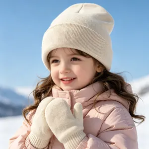 Close-up of a smiling girl wearing a cream knitted beanie and mittens in the snow