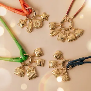 Macro view of 18k gold plated stainless steel star and handbag charms on colored cords