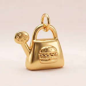 Detailed macro view of gold watering can pendant with hamburger relief and hearts