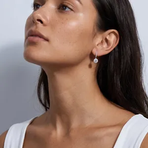 Elegant S925 silver dangling earrings worn by a model on a gray background.