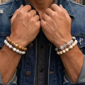 Nahaufnahme von gestapelten Herrenperlenarmbändern im Boho-Stil kombiniert mit einer Jeansjacke.