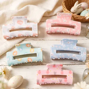 Set aus fünf pastellfarbenen Osterhasen- und Eierhaarspangen auf einem Holztisch.