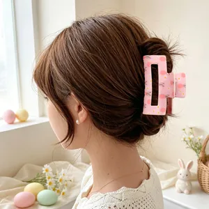 Nahaufnahme einer rosa Haarspange mit Osterhasen- und Ei-Muster in braunem Haar