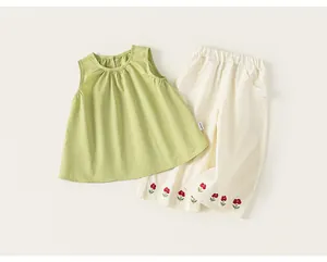 Dettaglio completo estivo da bambina con top a pieghe verde e pantaloni bianchi
