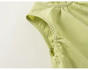 Dettaglio del giromanica e delle pieghe su un top senza maniche in cotone verde chiaro.