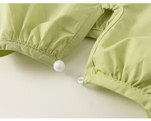 Dettaglio di top a pieghe verde lime con elegante bottone a perla e chiusura