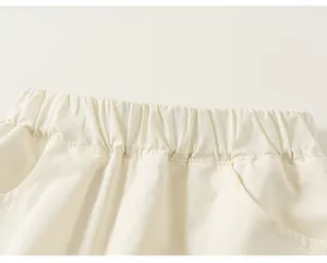 Dettaglio di vita elastica e tasche su pantaloni casual bianchi in cotone per bambini.
