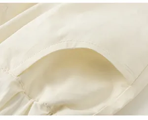 Dettaglio del tessuto plissettato bianco minimalista con cuciture fini per bambine