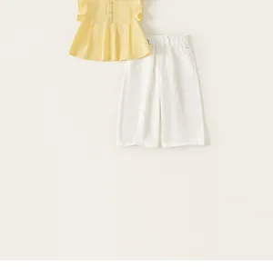 Vista dettagliata del set estivo da bambina con top giallo a pieghe e pantaloni bianchi casual