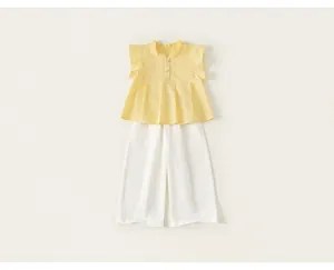 Dettaglio del set estivo 2 pezzi da bambina con top giallo a volant e pantaloni larghi bianchi