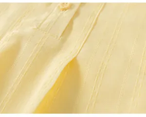 Macro dettaglio della trama del tessuto plissettato giallo pallido e bottone sul top bimba