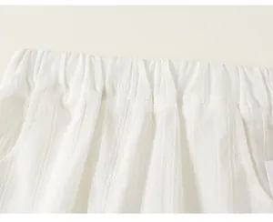 Dettaglio dei pantaloni casual bianchi da bambina con vita elastica e tessuto pieghettato.