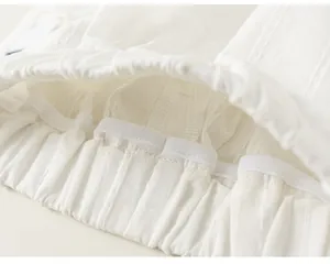 Dettaglio dell'elastico in vita e della trama del tessuto pieghettato dei pantaloni bianchi.