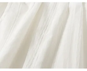 Vista dettagliata del morbido tessuto plissettato bianco per set estivo da bambina