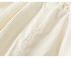 Primo piano di cuciture sottili su tessuto di cotone plissettato bianco per bambina.