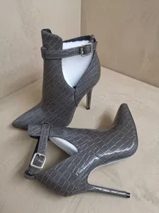 Nahaufnahme grauer Stiefeletten in Kroko-Optik mit hohem Absatz und seitlichem Ausschnitt