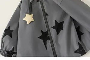 Close-up of gray children's windbreaker featuring black star patterns and zipper detail