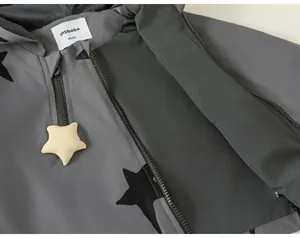 Close-up of children's grey windbreaker with star pattern and star zipper pull
