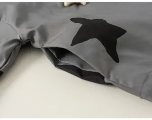 Close-up detail of the side pocket on a grey windproof girls' jacket with black star print