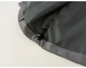 Close-up detail of the adjustable drawstring hem on a grey outdoor windbreaker jacket