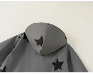 Detail view of children's gray hooded windbreaker jacket with black star pattern