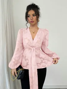 Detail of pink semi-transparent V-neck blouse with floral burnout pattern and waist tie.