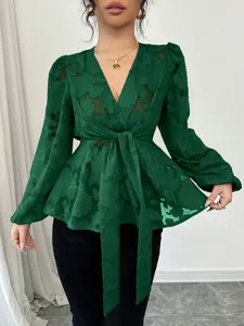 Detail view of dark green semi-transparent V-neck blouse with floral texture and tie waist.