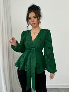 Close-up detail of women's emerald green V-neck blouse featuring burnout floral textures.