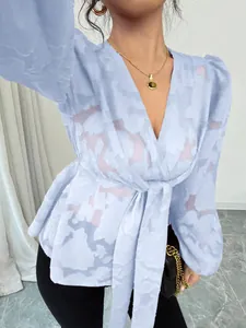 Detail of light blue semi-transparent V-neck blouse with jacquard texture and tie-waist.