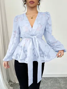 Detailed view of a light blue sheer jacquard long sleeve V-neck tie-front peplum blouse