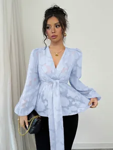 Close-up detail of a light blue sheer floral jacquard blouse with V-neck and tie-waist.