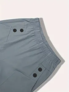 Close-up of high-waist plaid trousers with elastic waist and decorative buttons.