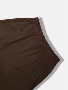 Close-up of elastic waistband and decorative button details on professional brown trousers.